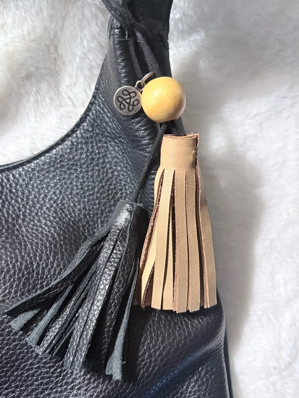 The Sak Black Leather Shoulder Bag with Tan Tassel Charm